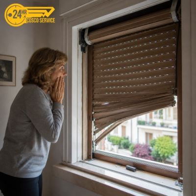 Signora sconvolta mentre osserva la tapparella che cade improvvisamente.